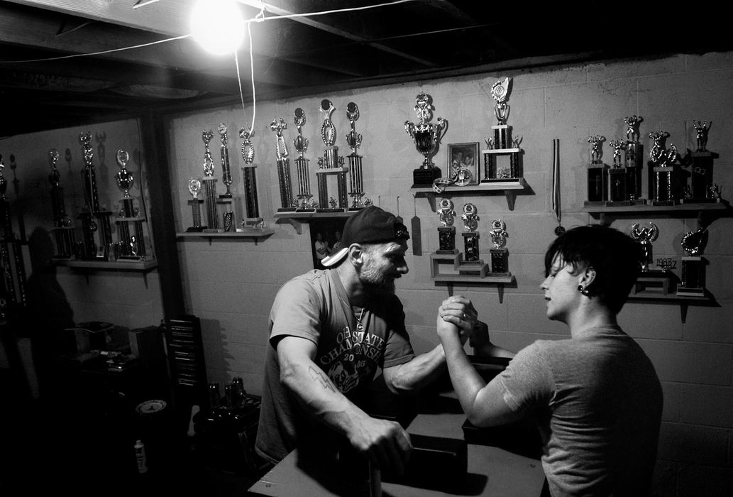 Second Place, George S. Smallsreed Photographer of the Year Award - Greg Ruffing / FreelanceWillie Reagan, who began his professional arm wrestling career in 1983, is now passing along his championship tradition to his 19-year-old son Boomer. At age 14, Boomer began competing in youth divisions at tournaments where his father was pulling in the adult classes. After a year of winning every youth tournament he entered, Boomer moved up and began competing against adults. Surrounded by trophies, Willie Reagan (left) and his 19-year-old son