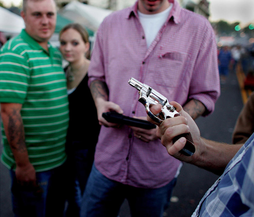 First place, Student Photographer of the Year Award - Katie Falkenberg / Ohio UniversityTeenagers in Mount Sterling, Ky., inspect a handgun for possible sale or trade on West Queen St. during the annual festival in October 2005. Firearms are commonly sold and traded without proper paperwork at this street festival. Each state has its own gun laws; however, in September of 2004, the assault weapons ban expired and was not renewed by Congress and the president. 