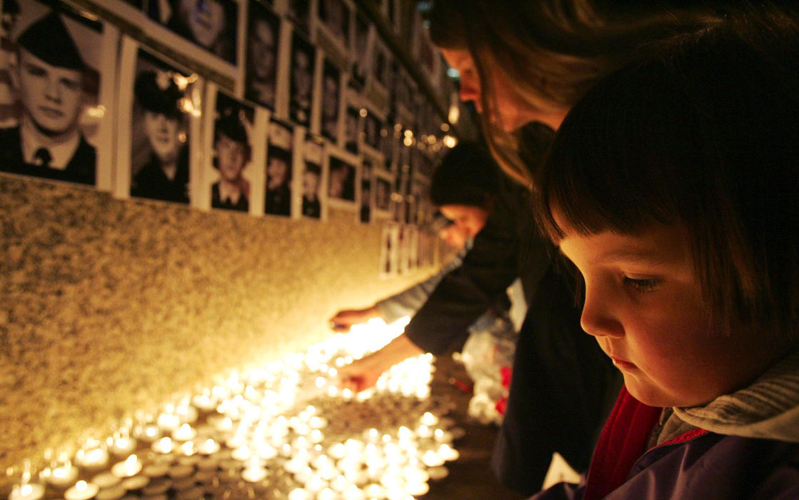 Second Place, Student Photographer of the Year Award - Emily Rasinski / Kent State UniversityFour-year-old Mary Rohrer looks down at the 2000 candles being lit at the Federal Building in Akron.  Elizabeth Dowling (center)  explained to Rohrer that the candles and pictures represent the soldiers killed in Iraq.  