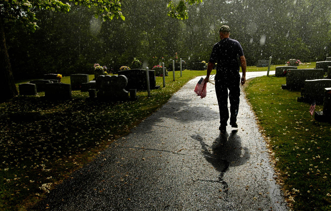 Third Place, Student Photographer of the Year Award - Michael P. King / Ohio UniversityAs raindrops fall and tree blossoms litter the ground, Clyde Breeden of American Legion Kapperman Post 44 walks through Rose Hill Cemetery in Newburgh, Ind., placing flags at the graves of war veterans in anticipation of Memorial Day, May 27, 2005. “Most of these names (on the graves) are names I’m familiar with,” said Breeden. "It's sad that we forget them."
