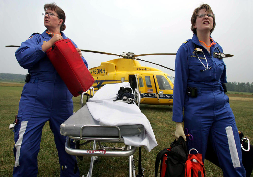 Award of Excellence, Student Photographer of the Year Award - Sung H. Jun  / Ohio UniversityLife Flight nurse specialist LIsa (left) and flight physician Sherri Clewell unload their portable equipment from the aircraft and wait for the ambulance carrying the trauma victim from the scene to arrive. Cleveland Metro Life Flight's crew often has little time to clean the blood from their equipment before responding to another call. This story is a day story following their 12 hour shift. 