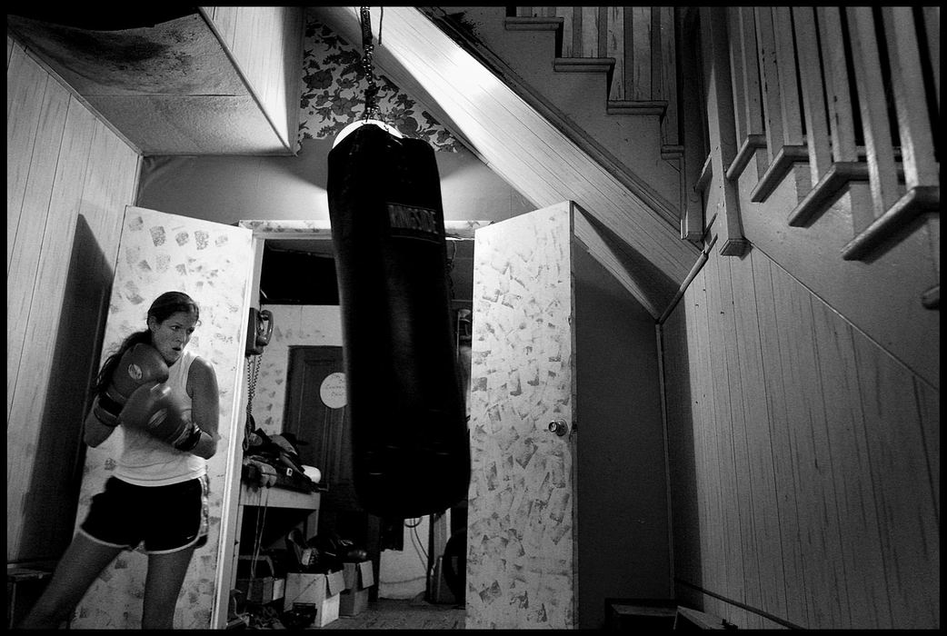 Second Place, Sports Picture Story - Katie Falkenberg / Ohio UniversityWith a bag set up below the staircase in the one-room gym, Jessica practices alone; she often resorts to this type of training when she has trouble finding a man who will fight her.