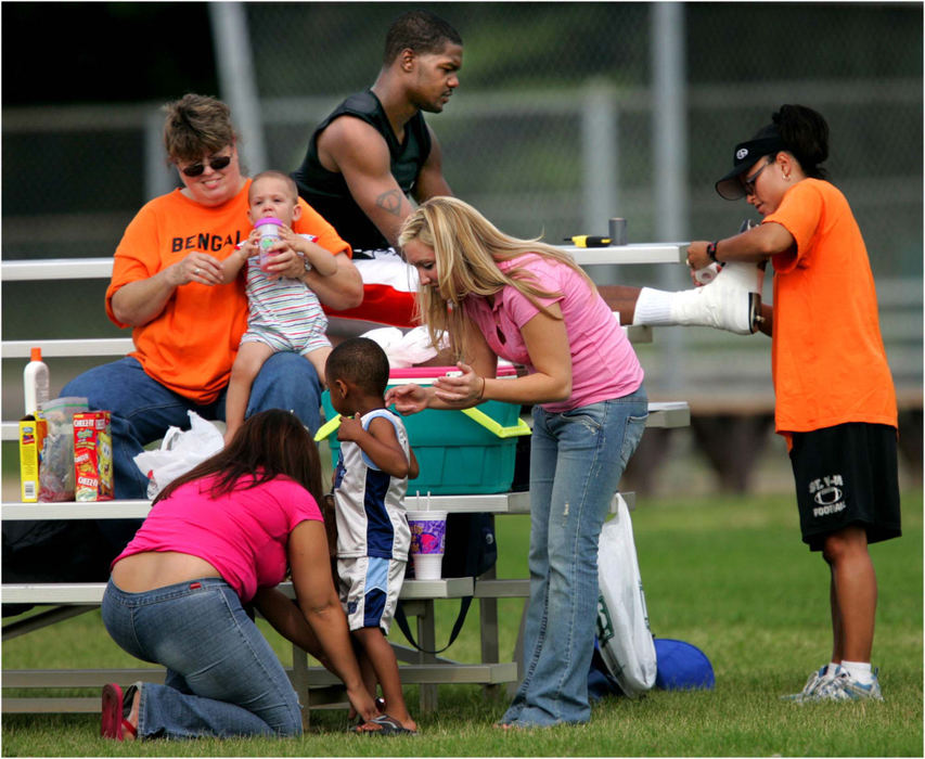 Award of Excellence, Sports Picture Story - Ed Suba, Jr. / Akron Beacon JournalGame days always had a picnic atmosphere and a loyal group of families and fans took full advantage of the summertime activity. At right,  Melissa Powers, acting trainer and wife of Ohio Valley Bengals head coach Ricky Powers, tapes the ankles of Dalvin Hill while Cathy Witt gives a drink to grandson Nathaniel King and two other team supporters put sun tan lotion on their kids before a game against the Mahoning Valley Panthers. 