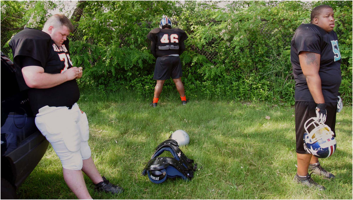 Award of Excellence, Sports Picture Story - Ed Suba, Jr. / Akron Beacon JournalOhioValley Bengal players Donnie Witt (left) and Jamar Holmes (right) try to kill time before a pre-season game while Nick Thompson (center) makes use of the bushes as a make-shift bathroom. Like many semi-pro teams, the Bengals were forced to play on a middle school field without any facilities because it was the only field available to practice on in the city that wasn't being used for other activities. More importantly, it was free. 