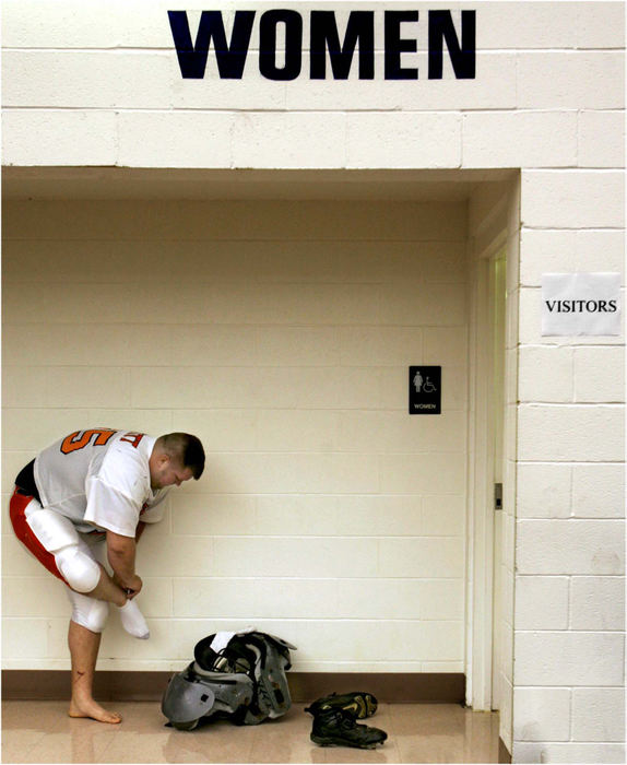 Award of Excellence, Sports Picture Story - Ed Suba, Jr. / Akron Beacon JournalOhio Valley Bengal player Donnie Witt dresses for the team's game against the Buffalo Warriors outside the visitor's locker room, a women's bathroom, at the Buffalo Bills training facility in Orchard Park, New York. It was just one of many reminders during the summer season just how far from the glamorous world of NFL football the players were.
