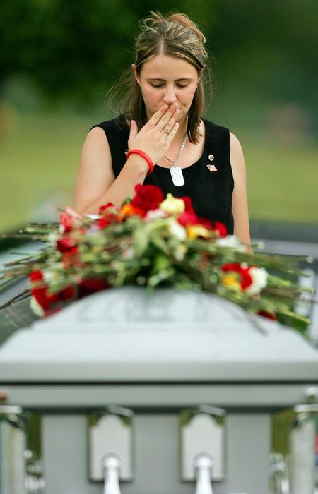 Second Place, Team Picture Story - JOHN KUNTZ / The Plain DealerPam Montgomery, wife of slain Marine Brian Montgomery of Willoughby, kisses her palm before laying it on the coffin of her husband to say goodbye after burial services August 10, 2005 at Western Reserve Memorial Gardens in Chester Township.   Pam Montgomery, wife of Marine Lance Cpl. Brian Montgomery, kisses her palm before placing it on her husband's coffin after burial services Wednesday at Western Reserve Memorial Gardens in Chester Township.