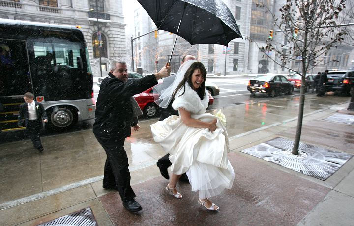 Award of Excellence, Enterprise Feature - Thomas Ondrey / The Plain DealerBride Coleen Conroy picked a wet and snowy day to marry, as her arrival beneath an umbrella held by limo driver Dave Sternad attests. Conroy and husband Jerry held their reception at the Hyatt Regency, downtown, despite predictions of 8 inches of snow arriving by midnight.