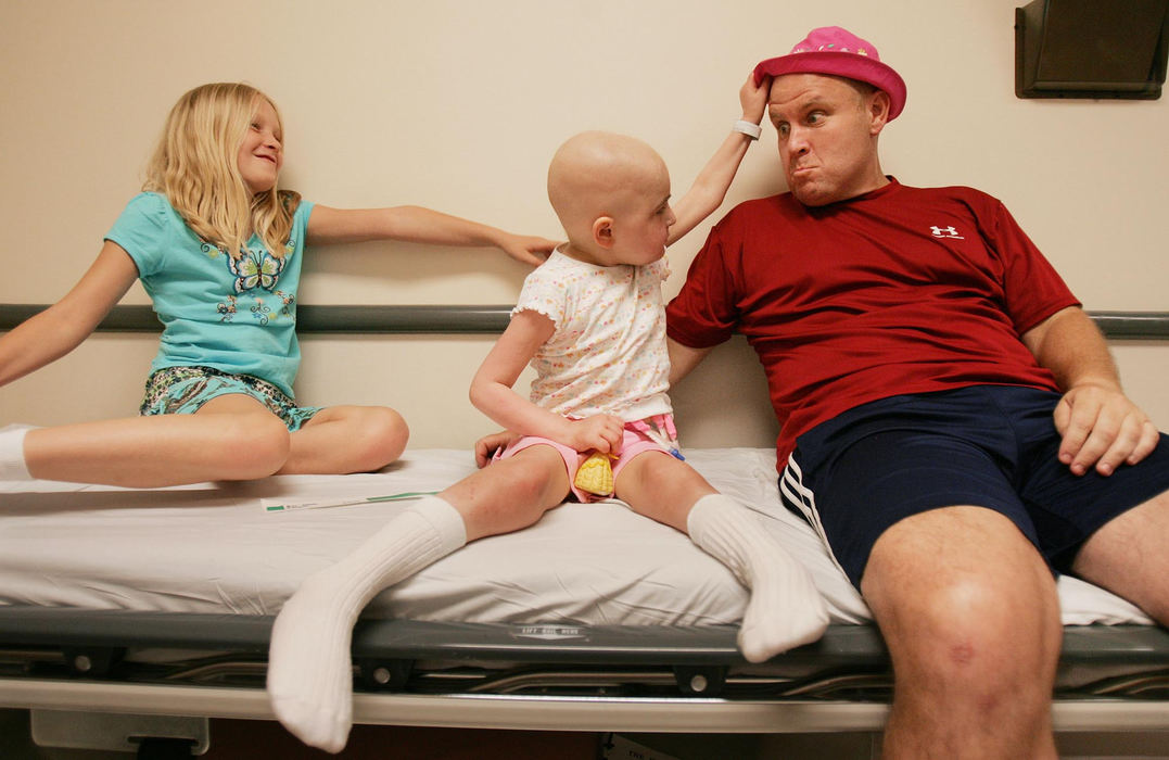 First Place, Feature Picture Story - John Kuntz / The Plain DealerDakota reaches up to get her hat back from dad, Ken, as sister Bailey enjoys the scene as they wait to get a room for their weekly check-up May 29, 2006 at Duke Medical Center in Durham, NC.   