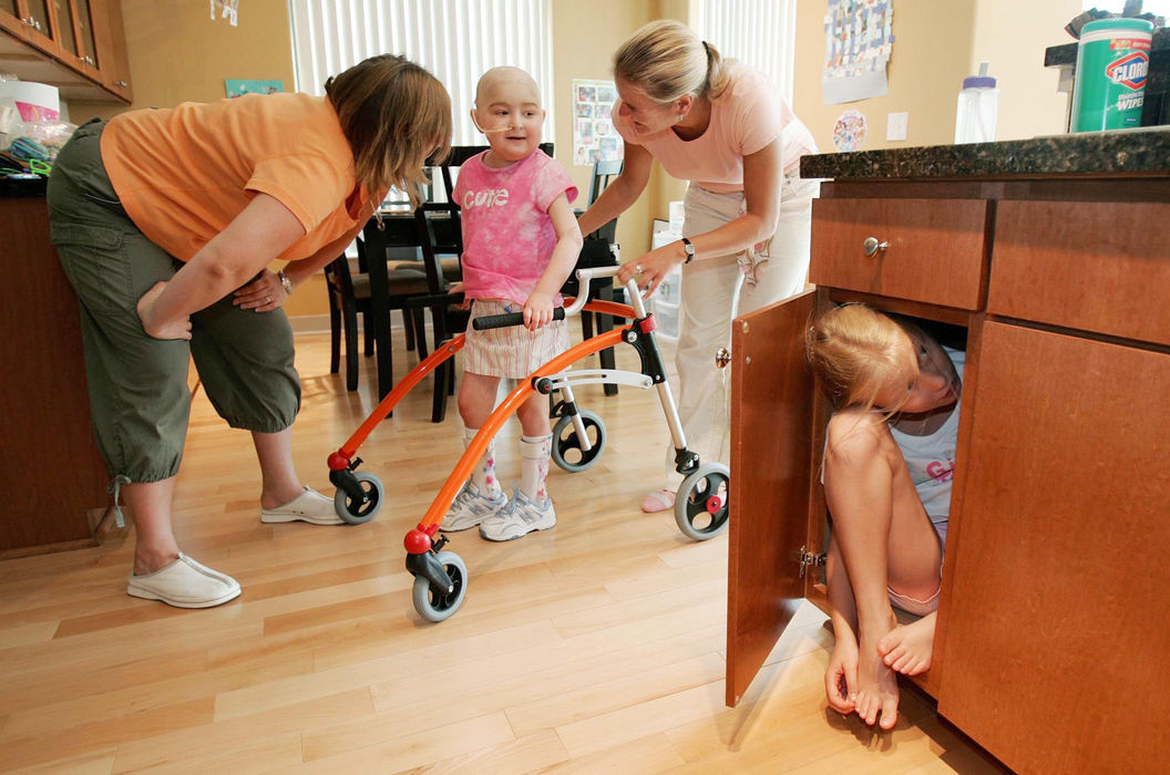 First Place, Feature Picture Story - John Kuntz / The Plain DealerBailey hides in a cupboard at the families temporary apartment in Durham, North Carolina as her sister Dakota tries to find her with the aid of a walker as she gets some exercise July 10, 2006.  