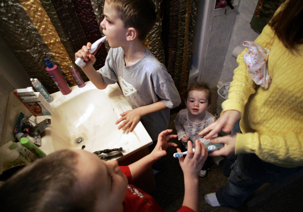 Third Place, Feature Picture Story - Chris Russell / The Columbus DispatchHolding a pair of Gabriel's diapers under her arms, Lee Ann gets the older boys ready for school while Reagan, 5, looks on and watches the early morning chaos.  