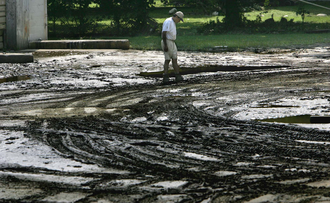 Third Place, News Picture Story - Thomas Ondrey / The Plain DealerJorge Hernandez inspects the parking area of an auto body shop in Painesville, now covered in the mud of the Grand River after yesterday's torrential rainfall.
