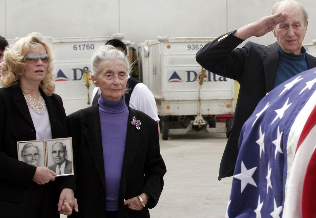 Award of Excellence, News Picture Story - Tim Revell / The Columbus DispatchFrom left: Christina Davis (daughter) and Mary Alice Foster and Don Foster react to the arrival of the flight  bringing the body of her brother Lt. Charles "Buddy" Feucht after his death in WWII 63 years ago. His body was discovered in New Guinea. Don Foster saluting is a WWII Navy Vet. The photos being held by Christina are those of her grandparents.