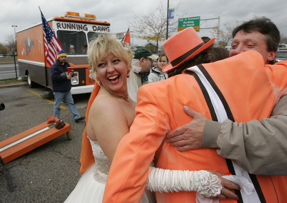 First Place, James R. Gordon Ohio Understanding Award - Joshua Gunter / The Plain DealerBruce and Dawn MacLaren sealed their love for one another, and for the Browns, with a kiss on a recent Sunday.  For die-hard Browns fans like Bruce and Dawn, the Muni lot was the perfect setting for their orange and white wedding. Amid the grilling of burgers, the downing of beers, and the tossing of beanbags, the two felt right at home saying their “I do's.” “We fought like cats and dogs,” Dawn said, laughing, her miniature Browns-helmet earrings wagging. “Then we kissed, and it was all over. He had my heart.”