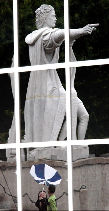 Second Place, Photographer of the Year - Chris Russell / The Columbus DispatchWilson Rahardjo and Ike Sutzipto pay the price for heading against the wind while the reflection of a statue of Christopher Columbus appears to be pointing the opposite way as they struggle with their umbrella on the campus of Columbus Community College.  