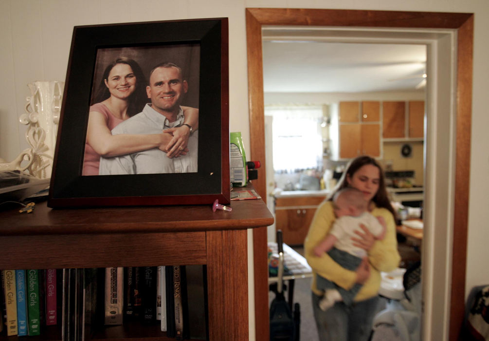 Second Place, Photographer of the Year - Chris Russell / The Columbus DispatchLee Ann Ivy carries newborn Gabriel through the living room doorway where a photograph of she and Staff Sgt. Ivy Kendall rests on a bookcase.  The photograph was taken on Kendall's last visit home and he would never meet his son, Gabriel.