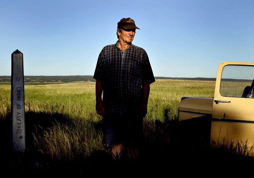 Third Place, Photographer of the Year - Greg Ruffing / FreelanceGuy Backman next to a cement monument marking the U.S.-Canada border adjacent to his homestead in Souris, North Dakota. Mr. Backman's family has farmed the land here for generations, dating back to the 1800s. Throughout North Dakota, much of the border is open farmland, prairie or sparse woods.