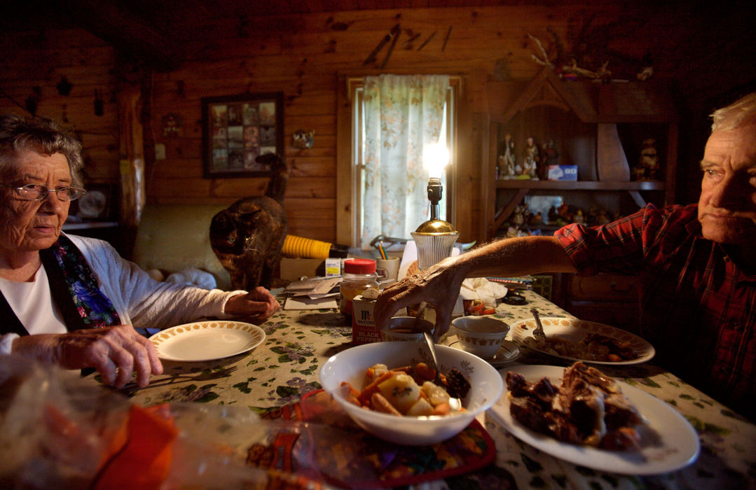 Second Place, Student Photographer of the Year - Michael P. King / Ohio UniversityBibbee and his friend Helen Findling share lunch together at Findling’s log home in Alfred, Oct. 1, 2006. Joining them at the table is one of Findling’s cats, Blackie. Since 1978, the relationship between Findling and Bibbee has been reciprocal, helping meet each other’s daily needs while providing companionship. Bibbee, unable to cook, is fed. Findling, unable to drive, is taken where she needs to go. Bibbee has no running water in his rural trailer home and carries water in a jug from Findling’s house for coffee and hygiene.