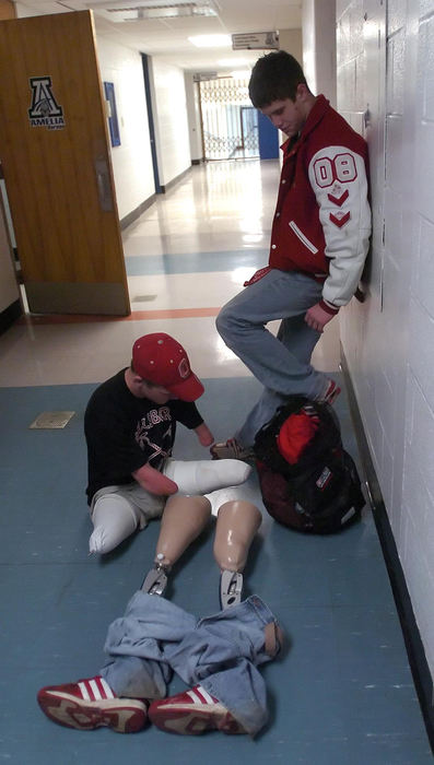First Place, Sports Picture Story - Jeff Swinger / Cincinnati EnquirerAfter a tough match Dustin wrestles with putting his prosthetic legs on while his buddy and teammate (right) Greg Rhoads waits for him before getting back on the bus for the late night trip back home.