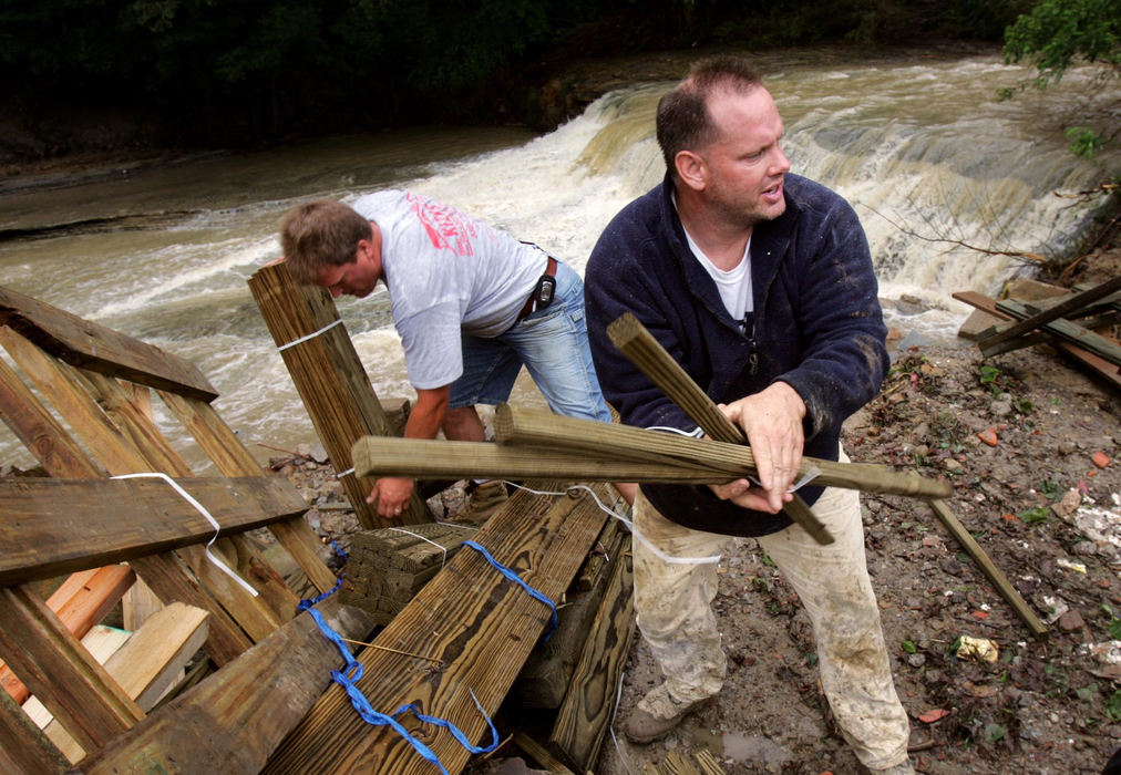 First Place, Team Picture Story - Marvin Fong / The Plain DealerTom VanMeter, in front, and Don Kizys help clean up at Larsen Lumber and Supply in Brecksville on Friday. Wood and other building materials were left scattered when the Chippewa Creek, in the background, flooded the business.