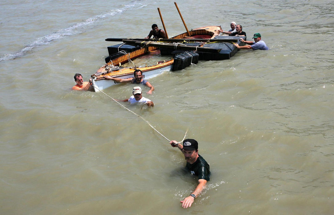 First Place, Team Picture Story - Thomas Ondrey / The Plain DealerA crew of volunteers pulls to safety the shattered wreck of the Moonfleet, an historic replica steam tender normally moored on the Grand River, but washed by the storm out into Lake Erie on July 29. The volunteers, led by Tom Jackson, front, found the boat two miles east of the river's mouth on a Lake Erie beach and walked its hull back to its dock.