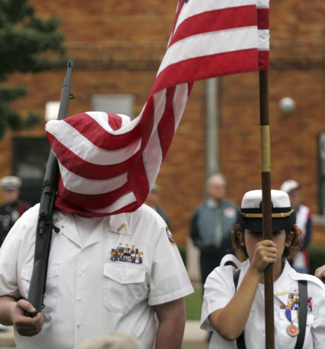 Third Place, Enterprise Feature - Jim Witmer / Dayton Daily NewsA well disciplined unidentified Piqua high school student NJROTC member (left) doesn't flinch despite being smothered by the American flag during a breezy ceremony at the Piqua American Legion in an early morning ceremony honoring WWII veterans leaving for Washington D.C. Holding the flag is fellow member Joelle Mesojednik. 