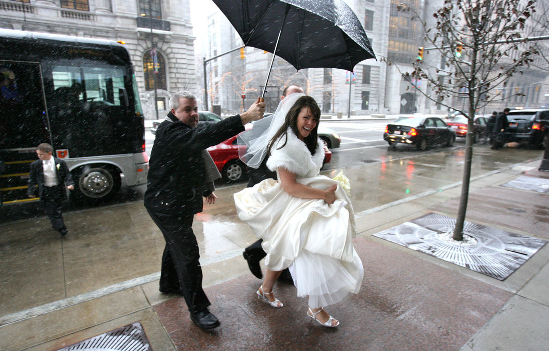 Award of Excellence, Enterprise Feature  - Thomas Ondrey / The Plain DealerBride Coleen Conroy picked a wet and snowy day to marry, as her arrival beneath an umbrella held by limo driver Dave Sternad attests. Conroy and husband Jerry held their reception at the Hyatt Regency, downtown, despite predictions of 8 inches of snow arriving by midnight.