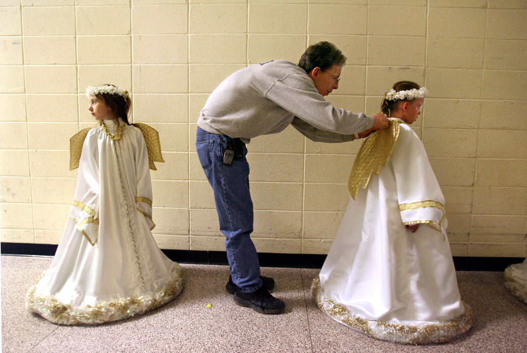 Award of Excellence, Feature Picture Story - Lisa DeJong / The Plain Dealer   "This is my little angel," says Rick Kenney as he pins gold wings onto his daughter Hallie's angel costume.  Kenney is helping out with final touches just before she goes onstage during dress rehearsal practice for Ohio Dance Theater's "Nutcracker".  In minutes, seven-year-old Hallie would be floating across the stage through smoke and deep blue lights, a vision of celestial perfection, dancing in her very first Nutcracker ballet.    