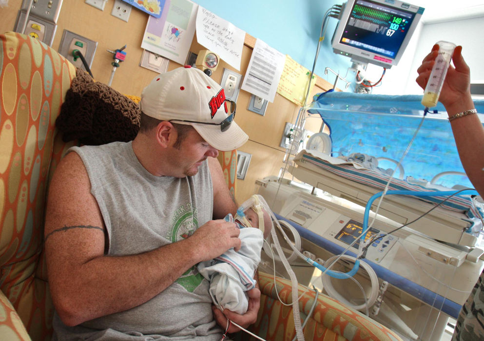 First Place, Feature Picture Story - Chris Russell / The Columbus DispatchBeth holds up a beaker of breast milk that is delivered to Riley by a tube directly into his stomach while John holds him for the first time.  Riley has grown enough to be out of his incubator but still must be fed by IV and is still on a respirator that breathes for him.  