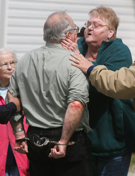 Second Place, News Picture Story - Phil Masturzo / Akron Beacon JournalAlexander Campbell, in handcuffs, is calmed by a neighbor as he is taken away from his home after a hour-long standoff with Akron Police. 