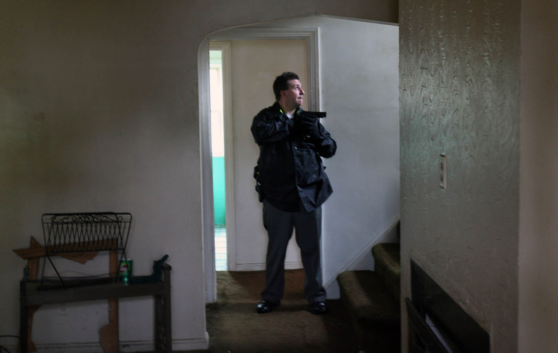 First Place, News Picture Story - Gus Chan / The Plain DealerCuyahoga County Sheriff Deputy David Rowe watches the upstairs as his partner checks the remainder of the downstairs in a home on Talford Ave. 