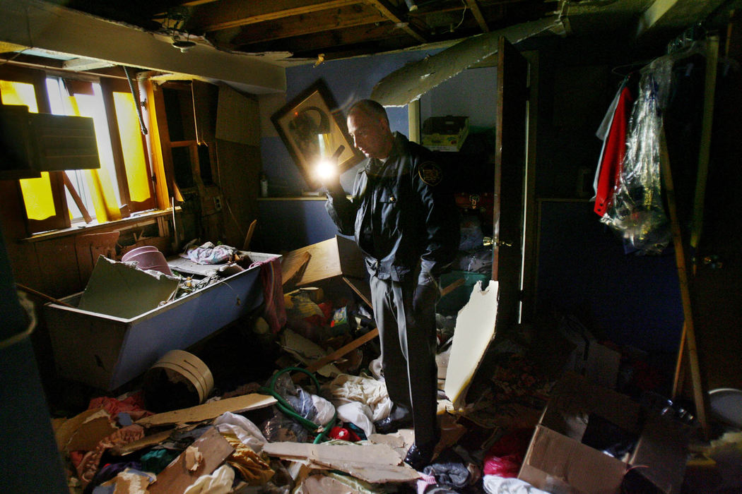 First Place, News Picture Story - Gus Chan / The Plain DealerCuyahoga County Sheriff Deputy Rob Kole surveys the basement of a Dynes Ave. home  where the copper plumbing and water heater were taken out. 