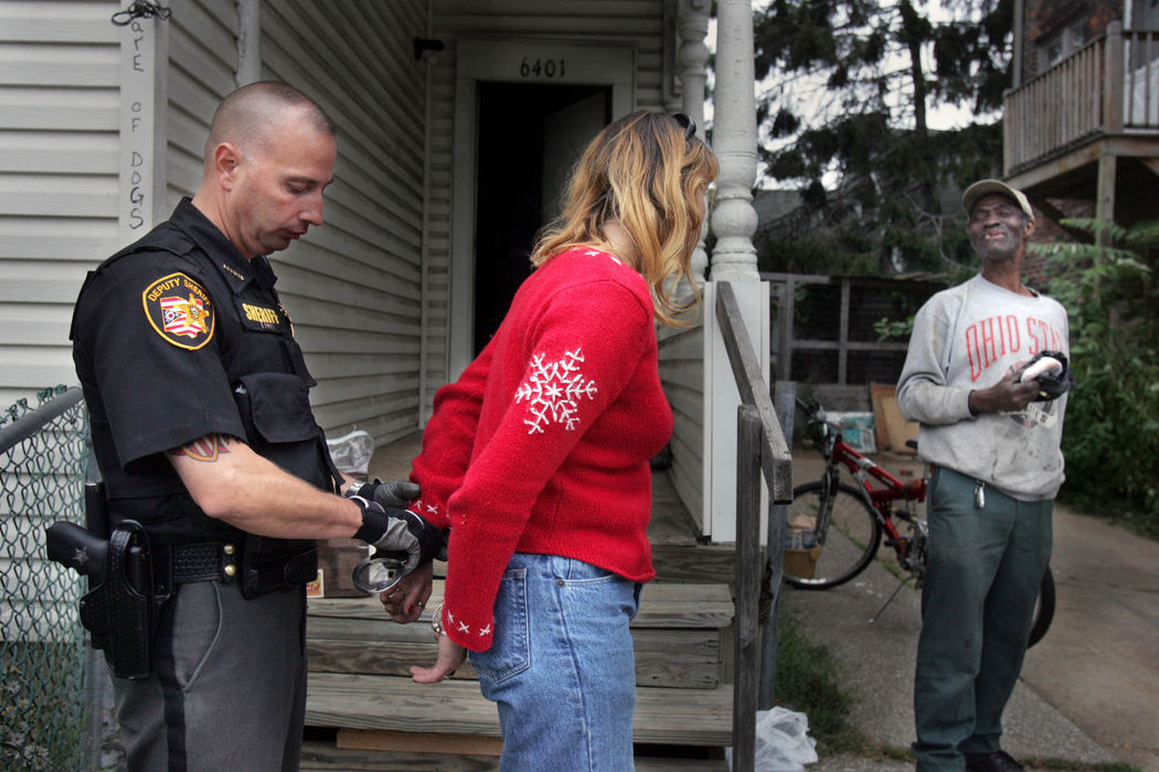 First Place, News Picture Story - Gus Chan / The Plain DealerCuyahoga County Sheriff Deputy Rob Kole, arrests a woman who had a warrant for parole violation while serving an eviction Wednesday, October 3, 2007.  The other tenant in the house laughs at the woman's predicament.  