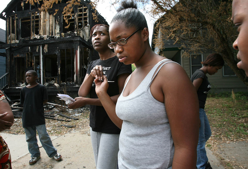 Second Place, Photographer of the Year - Lisa DeJong / The Plain DealerRogina Weakley (center) fearfully looks across the street at her neighbor's window where a video camera has been pointed towards her home, in background, for weeks.  Weakley and her daughters Marrielle Weakley, 12, with glasses, and Marika Fleming, 13, far right, visit the burnt remains of their home where an arson fire broke out while they were home. Weakley suspects that her neighbor, who is white, is responsible for the fire. Two arson fires at the homes of black families, punctuated with ugly scrawls of racist graffiti, has shocked neighbors in Cleveland's Tremont neighborhood. 