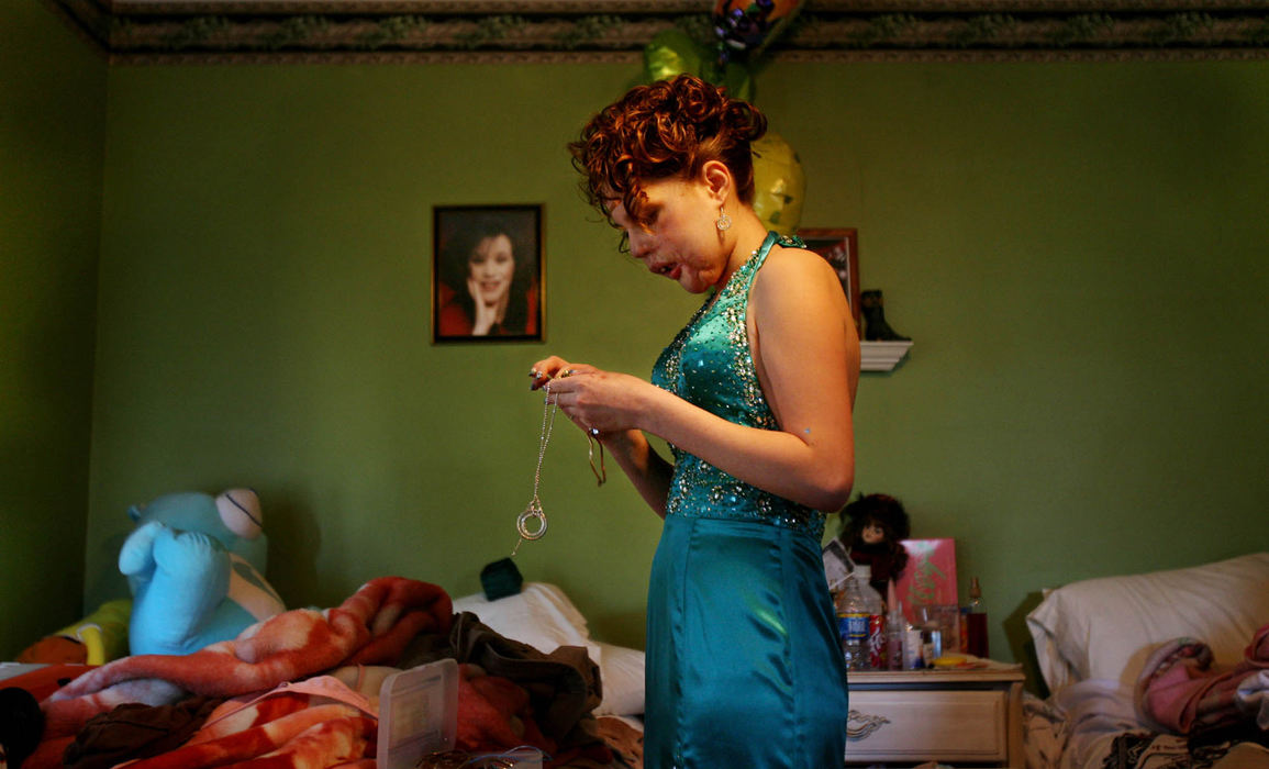 Third Place, Photographer of the Year - Gus Chan / The Plain DealerJohanna Orozco dresses for prom.  A portrait of her mother hangs on her wall.  