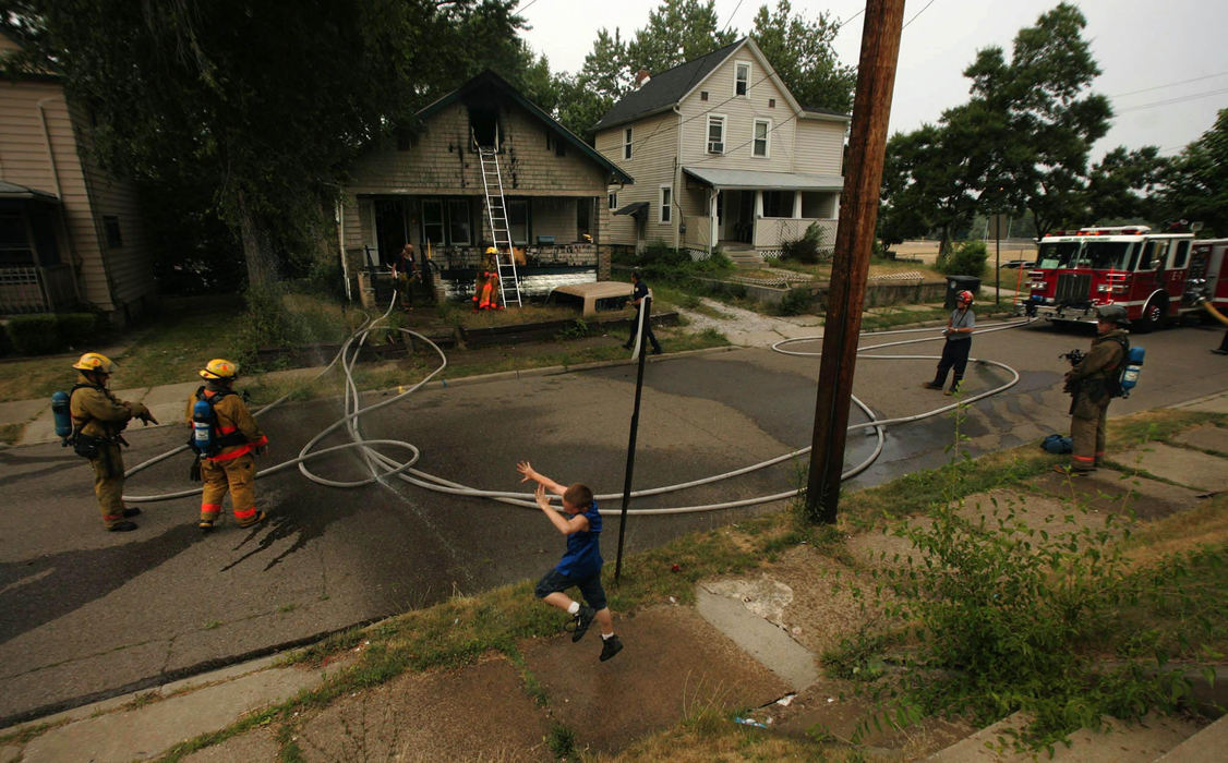 Award of Excellence, Photographer of the Year - Ken Love / Akron Beacon JournalA child dances along on the sidewalk while Akron firefighters work at the scene of an abandoned house fire.