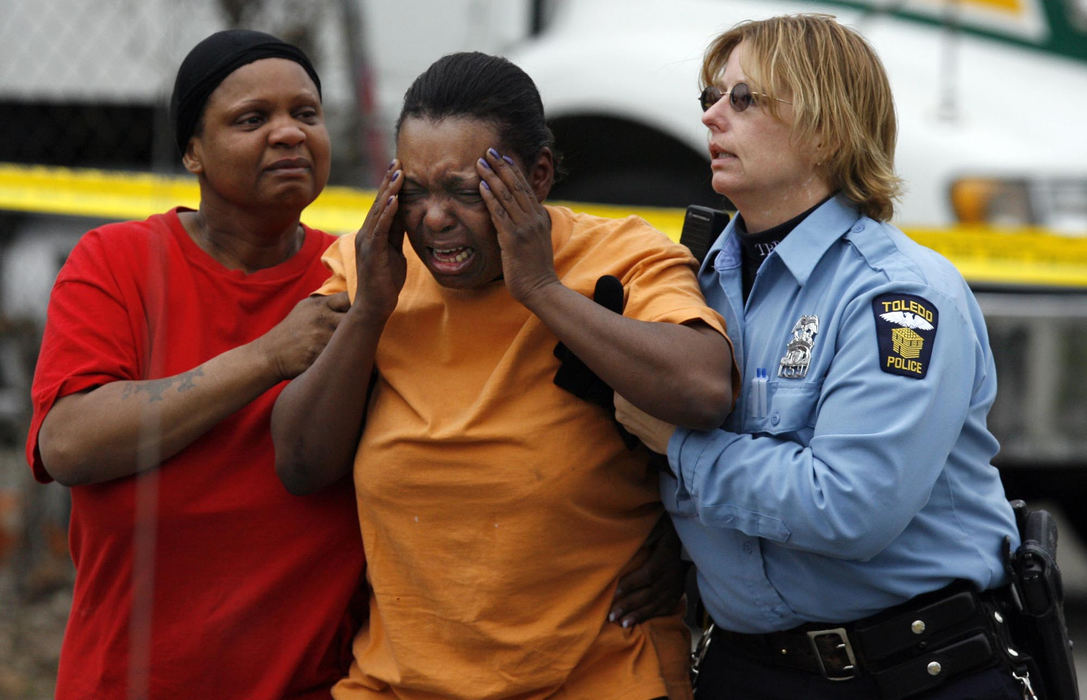 Award of Excellence, Spot News over 100,000 - Jeremy Wadsworth / The Blade A police officer and a relative assist Michelle Horton after she found out her son Ricardo Horton, 28, shot to death March 31, 2007, at the intersection of Mott Street and Elgin Street in Toledo. 