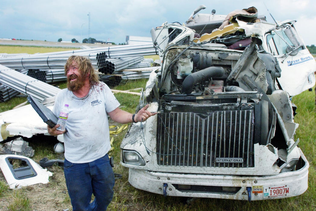 Award of Excellence, Spot News under 100,000 - Luke Wark / Sandusky RegisterTom Roberts of Chippewa Falls, Wis. was in good spirits while being questioned after retrieving his laptop from the remains of the semi truck he rolled on the Ohio Turnpike east-bound exit ramp at Ohio-4. Roberts lost control of his rig while exiting and rolled the semi into a small field, walking away with only minor cuts and bruises. 