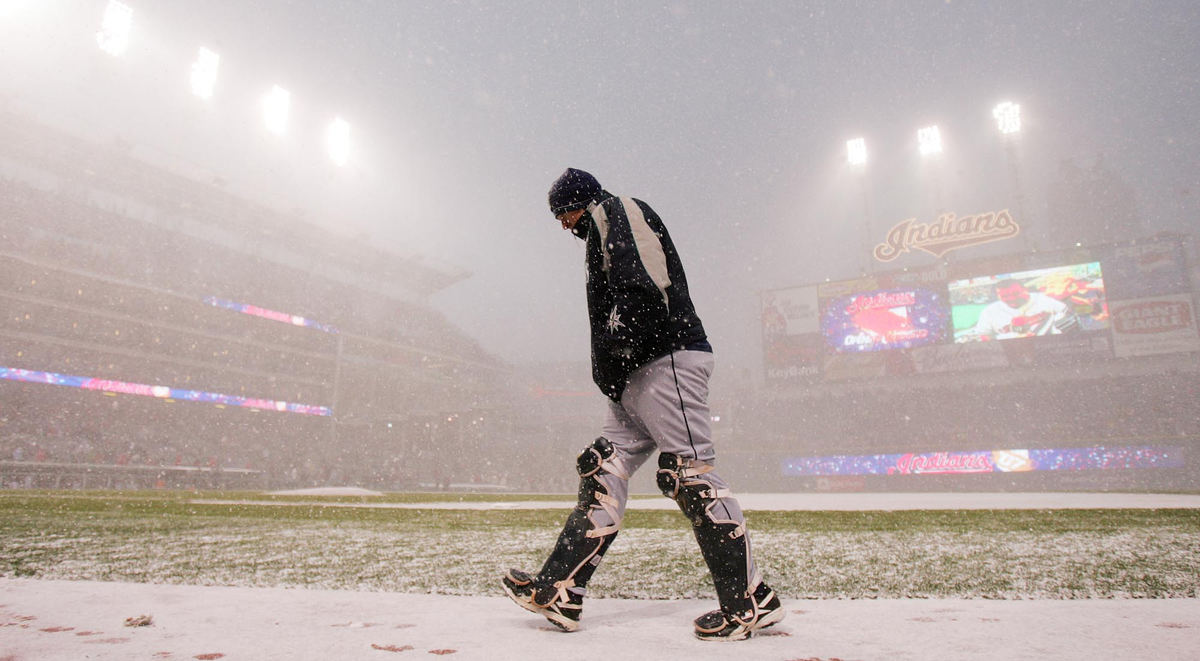 Second Place, Team Picture Story - JOHN KUNTZ / The Plain DealerSeattle Mariners back up catcher Jamie Burke walks to the dugout on the third snow delay in the fifth inning with the stadium background hardly visible in the snow squall during the Indians home opener. 