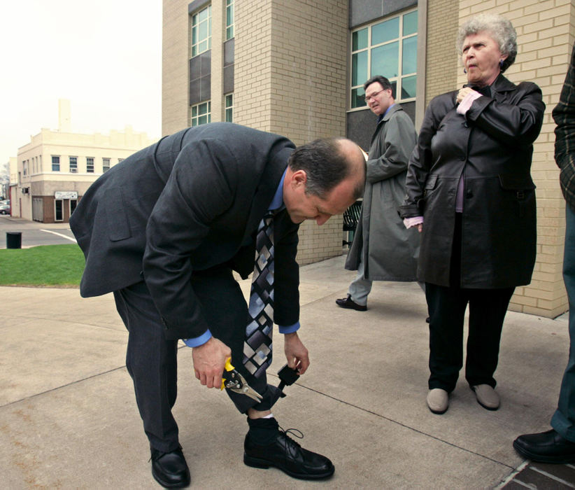 Third Place, Team Picture Story - Mike Cardew / Akron Beacon JournalAfter his acquittal at the Portage County courthouse Randy Resh cuts off the electronic monitor he has worn since January while he was free on bond.