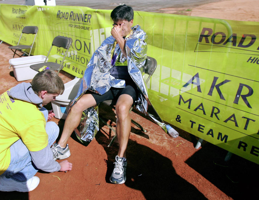 Award of Excellence, Team Picture Story - Phil Masturzo / Akron Beacon JournalVolunteer Glenn Clark unhooks the timing chip for an exhausted Sam Parri of Fairlawn after he finished running in the 5th annual Road Runner Akron Marathon.