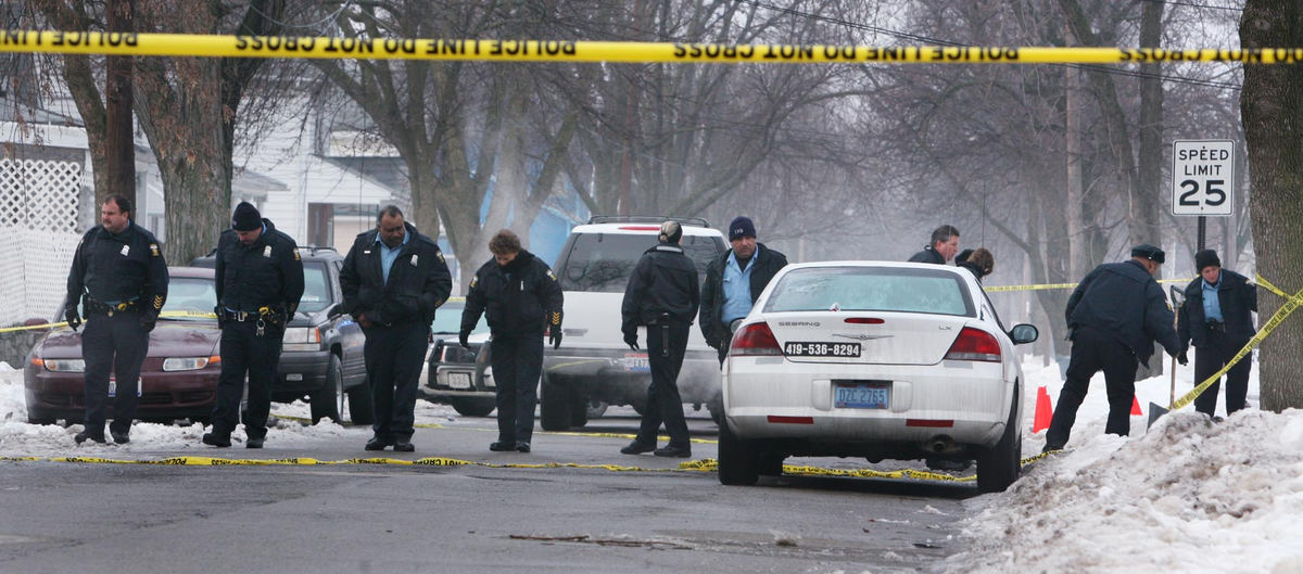 Award of Excellence, Team Picture Story - Lisa Dutton / The BladeToledo police canvas site of the shooting on Bush St. as they look for shell casings or other clues that might help in the case of the the shooting of TPD vice detective Keith Dressel was shot and killed in North Toledo.  