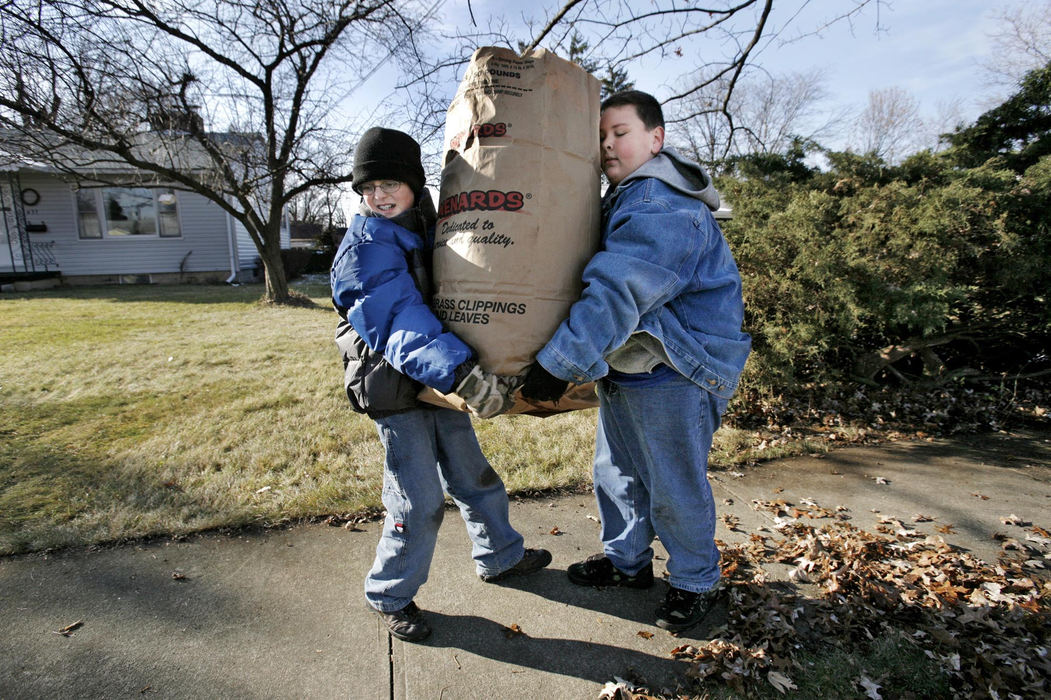 Third Place, Feature - Fred Squillante / The Columbus DispatchWeblos Scouts Devin Potter (left) and Bradly Heizer, both 11, move a heavy bag of leaves as they volunteer their leaf-raking services in Marion. They were among volunteers sprucing up the yards of the elderly or disabled.