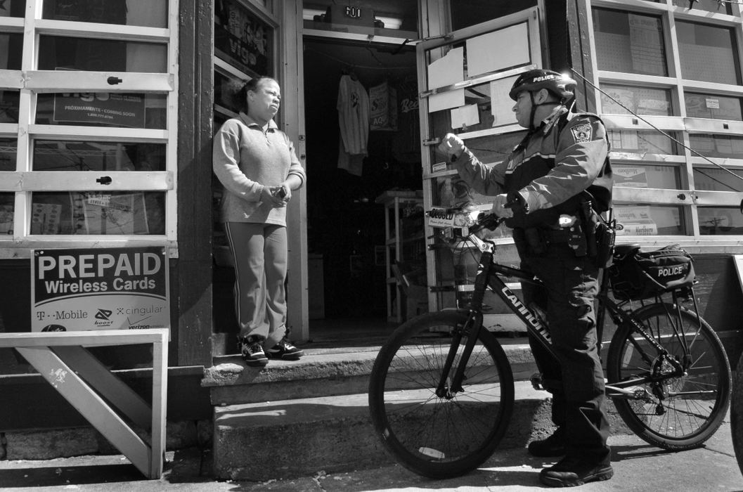 Third Place, Feature Picture Story - Carrie Cochran / The Cincinnati EnquirerHamilton Police Officer Eric Taylor talks talks to the Jasmin store owner March 12, 2008 in the Fourth Ward in Hamilton. She tells him that she just installed new security bars because she has recently been broke into twice. She doesn't think the acts were for money, though, because nothing was taken. She believes it's because someone doesn't want her here because she's Hispanic. 