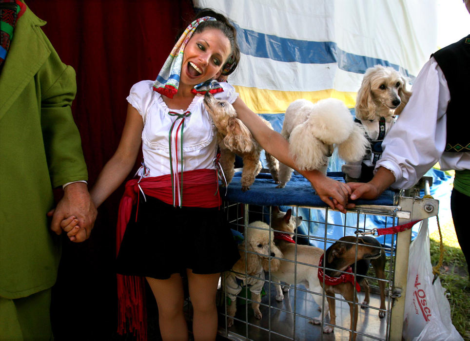 Award of Excellence, Feature Picture Story - Lisa DeJong / The Plain DealerAerialist Amy Riccio gets a sneak kiss from Lady during the performers' prayer circle just before the first show at the Great Lakes Medieval Faire. Before each and every show, all performers grab hands and take turns at a prayer. The dogs are members of "Rudolf's Performing Canines from Bavaria". 