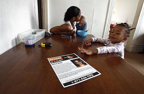 First Place, Feature Picture Story - Chris Russell / The Columbus DispatchMelvin's sister Kaykimia, 15, eats breakfast while Tyra, 4, plays with  one of the posters that were printed to encourage witnesses to Melvin's killing to come forward. It was not until the spring of 2008 that police finally identified suspects in the case.  The reluctance to testify in the gang infested neighborhood is common.