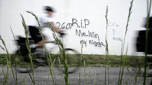 First Place, Feature Picture Story - Chris Russell / The Columbus DispatchA member of the Columbus Police Department's bike patrol passes by graffitti sprayed on the wall of a local church that memorializes Melvin's death. 