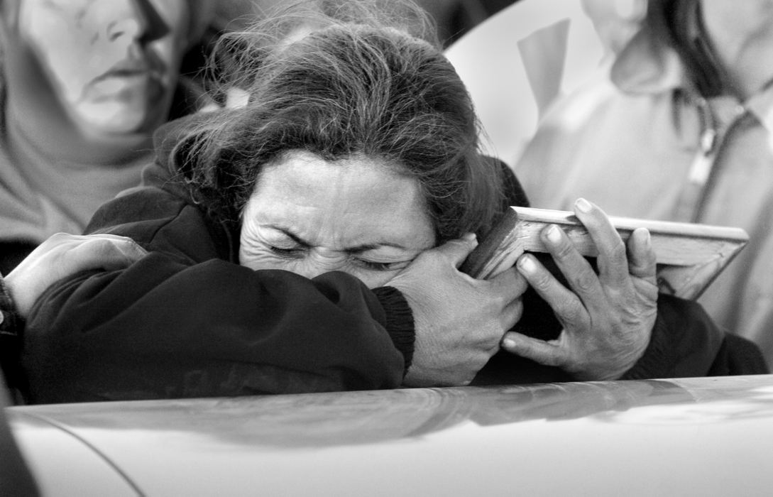 Second Place, News Picture Story - Carrie Cochran / Cincinnati EnquirerGuillermina Guardado Davila, 38, clings onto a photo of her son, Conrado Lopez Guarado, 20, as people try to pry her away so that the caskets can be put into the ground. The photo came home with her son's body, but she will wasn't able to see him in person. She hadn't seen him since he left to work illegally in the U.S. when he was 17 years old. She lost a father, a brother and a son all in a matter of months -- the last two killed together in Cincinnati in December.