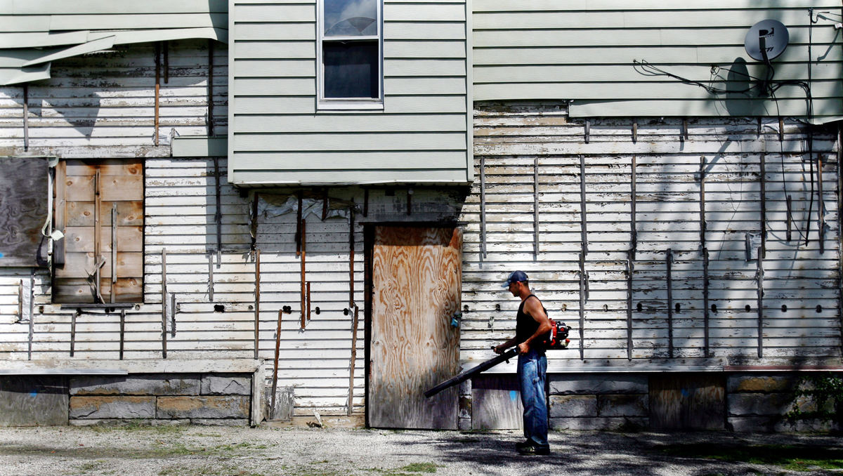 Award of Excellence, News Picture Story - Gus Chan / The Plain DealerRadu Onet puts the finishing touches on a boarded up home on E. 71 St.  Onet works for Sunra Services which cuts the grass on foreclosed properties.