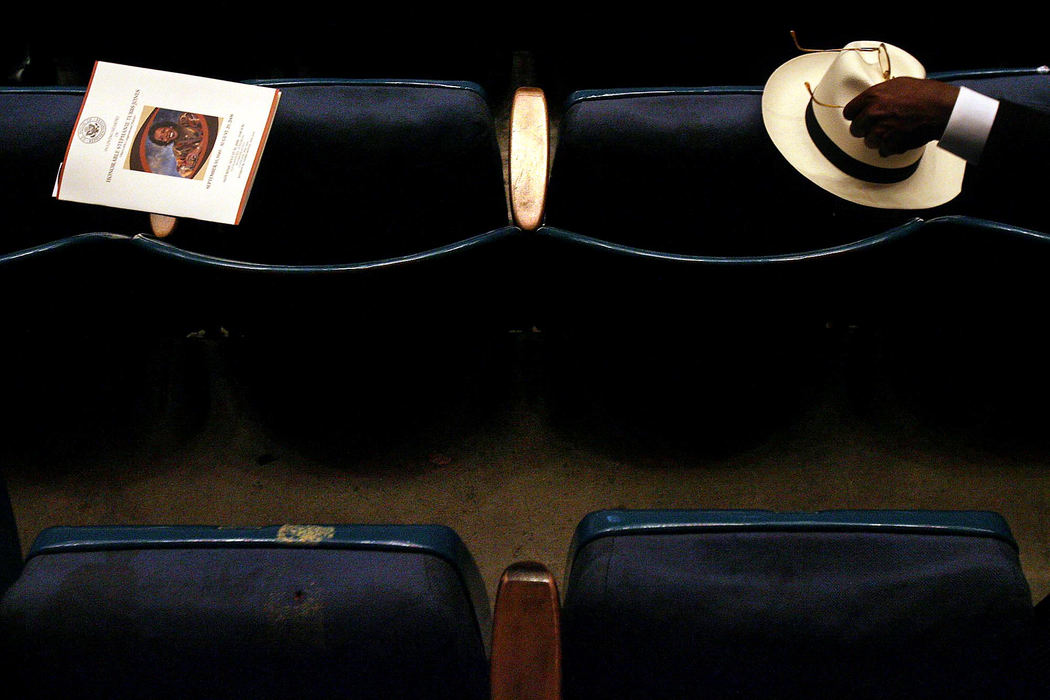 Third Place, Pictorial - Lisa DeJong / The Plain DealerA program and hat rest on folded seats as a mourner reaches for his glasses at the funeral for US Congresswoman Stephanie Tubbs Jones at Public Hall in Cleveland. Tubbs, a staunch Hillary Clinton supporter, didn't live to see the historic election. Tubbs died of an unexpected brain aneurysm. 