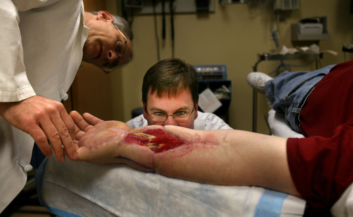 Third Place, Photographer of the Year - Gus Chan / The Plain DealerDr. Bram Kaufman, left, and Dr. Kevin Malone, center, examine the surgically attached left arm of Norm Martin.  Kaufman and Malone were to of the three surgeons who headed teams that reattached Martin's two arms.